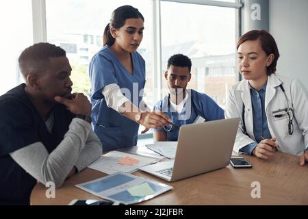 Setzen in die langen Stunden. Schoss eine Gruppe von Ärzten, die im Büro bei der Arbeit über Arbeitsangelegenheiten diskutierten. Stockfoto