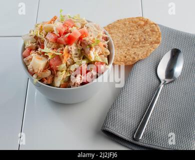 Thunfischsalat mit Salatmayo-Karottenstreifen und roten Paprika oben mit einem Löffel und einer Tostada an der Seite, Seitenansicht Stockfoto