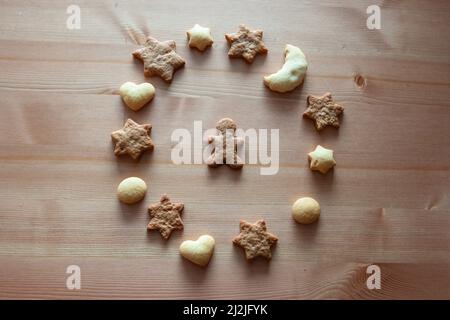 Verschiedene Figuren von Ingwerkeksen auf einem Holztisch. Rundes Plätzchen-Muster auf Holzhintergrund. Weihnachtskekse, Sternfiguren, Herz Stockfoto