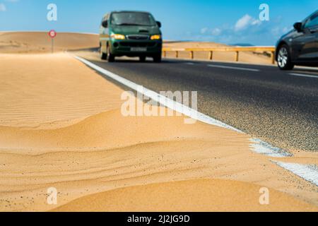 Autos fahren auf Asphaltstraße in der Wüste, Corralejo Naturpark, Fuerteventura, Kanarische Inseln, Spanien Stockfoto