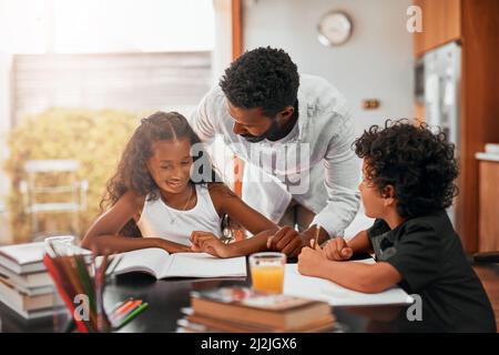 Legen Sie einen regelmäßigen Zeitplan für die Durchführung von Hausaufgaben fest. Aufnahme eines Vaters, der seinen Kindern bei ihren Hausaufgaben hilft. Stockfoto