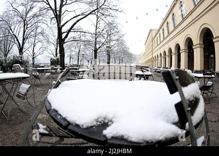 München, Deutschland. 02. April 2022. Die Tische sind im Hofgarten mit Schnee bedeckt. In München hat es geschneit. Quelle: Felix Hörhager/dpa/Alamy Live News Stockfoto