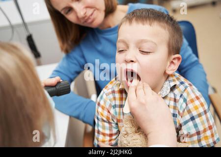 Kinderarzt untersucht den Kehlkopf des Kindes mit Zungendepressor Stockfoto