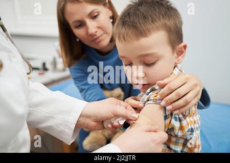 Arzt legt medizinischen Putz auf Kinderarm nach der Impfung Stockfoto