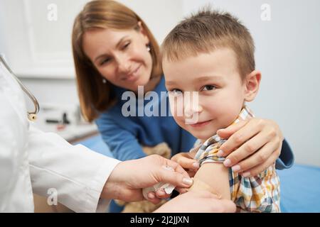 Kinderarzt legt nach der Impfung medizinischen Pflaster auf den Kinderarm Stockfoto