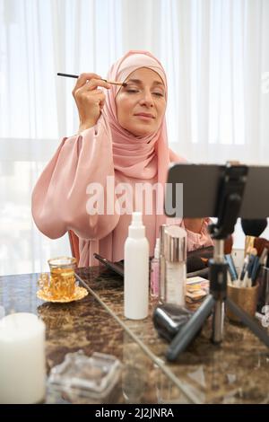 Calm Dame in Hijab versucht natürliche Farbe der Kosmetik Stockfoto