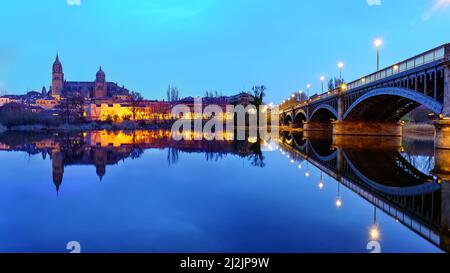 Nächtliches Stadtbild der Stadt Salamanca und des Flusses Tormes mit seiner Eisenbrücke. Stockfoto