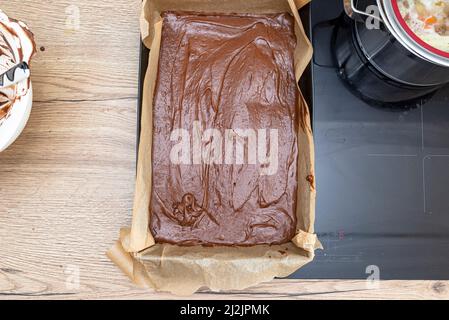 Backblech, komplett gefüllt mit dicker Kakaomasse, fertig zum Backen, auf der Küchentheke liegend. Stockfoto