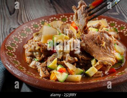 Ohne Knochen Hühnerschenkel mit Zwiebeln, Paprika, Zucchini, Knoblauch, Kartoffeln und Gewürzen, Auf einer mexikanischen Schlammplatte. Stockfoto