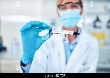 Leider hat dich die Infektion erwischt. Nahaufnahme eines nicht erkennbaren Wissenschaftlers, der ein mit Blut gefülltes Reagenzglas mit einem positiven Covid-19 hält Stockfoto