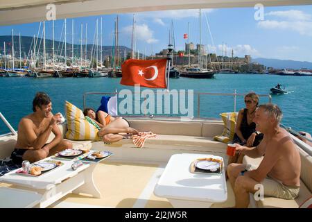 Sonnenbaden auf dem komfortablen Achterdeck einer Yacht, im Hintergrund die St. Peter Burg, Wahrzeichen von Bodrum, Türkei, Mittelmeer Stockfoto