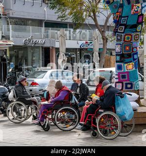 Netanya, Israel - 7. Februar 2022: Eine Gruppe älterer Menschen in Rollstühlen, die mit Sozialarbeitern im Park spazieren gehen. Nahaufnahme. Stockfoto