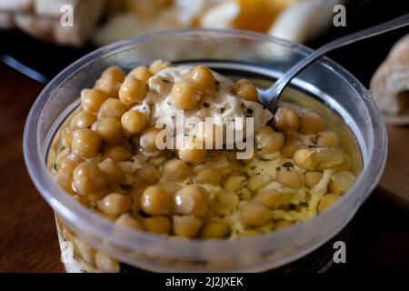 Hausgemachte Hummusschale, dekoriert mit gekochten Kichererbsen, Kräutern, Pita und Olivenöl auf einem rustikalen Metallhintergrund. Draufsicht. Stockfoto