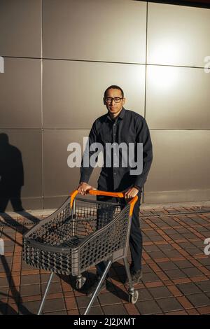 afro-Shopping mit einem Einkaufswagen, der Typ ist in der Nähe der Mall einkaufen Stockfoto
