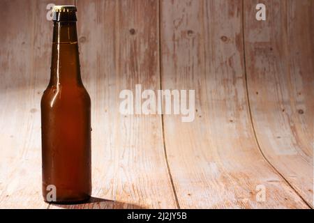 Geschlossene Bierflasche auf hellem Holzhintergrund Stockfoto