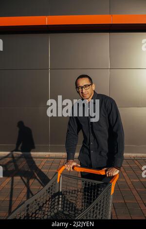 afro-Shopping mit einem Einkaufswagen, der Typ ist in der Nähe der Mall einkaufen Stockfoto
