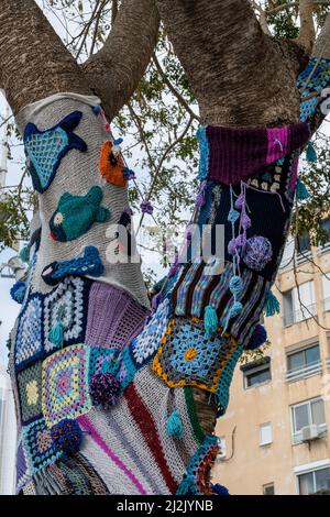 Bunte Häkelstrick auf einem Baumstamm Garn Bombing. Patchwork gestrickter, gehäkelter Baum für Wärme, Schutz und Dekoration. Hohe Auflösung Stockfoto