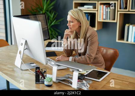 Sie denkt bei jeder Geschäftsentscheidung sorgfältig nach. Aufnahme einer reifen Geschäftsfrau, die in einem Büro an einem Computer arbeitet. Stockfoto