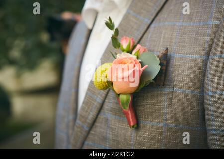 Nahaufnahme des schönen Boutonniere auf der Jacke des Bräutigams. Weicher Fokus auf boutonniere. Bildmaterial Stockfoto