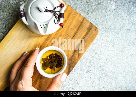 Frau, die nach einer Tasse grünen Tee greift Stockfoto