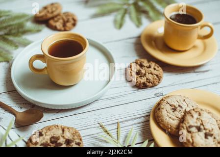 Zwei Tassen schwarzen Kaffee und Schokoladenkekse auf einem Tisch Stockfoto