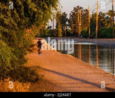 Ein Mann, der an einem sonnigen Nachmittag mit dem Fahrrad in der Nähe des Arizona-Kanals im Paradise Valley, einem Vorort von Phoenix, fährt Stockfoto