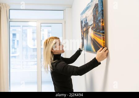 Fotoleinwand. Eine Frau, die eine Fotografie mit Gallery Wrap hält. Foto auf glänzendem Kunstleinwand gedruckt und auf Trageriegel gestreckt Stockfoto