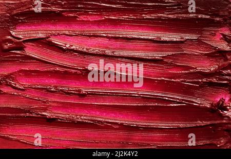 Abstrakter roter Abstrich von glänzendem Lippenstift, Makrofotografie der Textur. Stockfoto