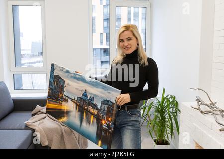 Fotoleinwand. Eine Frau, die eine Fotografie mit Gallery Wrap hält. Foto auf glänzendem Kunstleinwand gedruckt und auf Trageriegel gestreckt Stockfoto