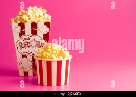 Rot-weiß gestreifter Popcorn-Eimer isoliert auf einem rosa Hintergrund Stockfoto