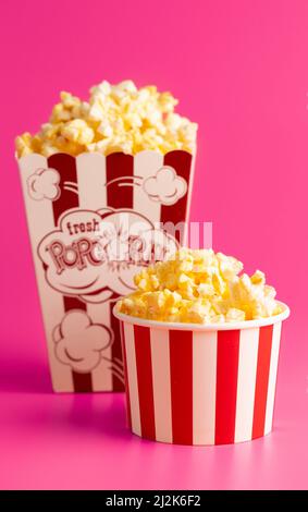 Rot-weiß gestreifter Popcorn-Eimer isoliert auf einem rosa Hintergrund Stockfoto