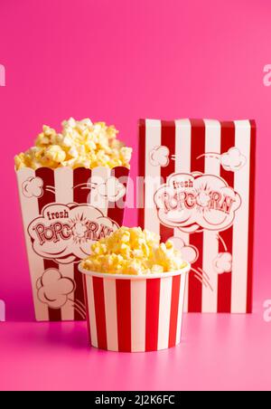 Rot-weiß gestreifter Popcorn-Eimer isoliert auf einem rosa Hintergrund Stockfoto