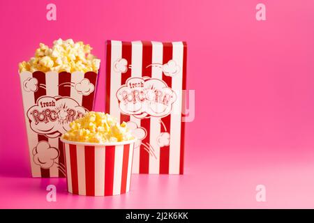 Rot-weiß gestreifter Popcorn-Eimer isoliert auf einem rosa Hintergrund Stockfoto
