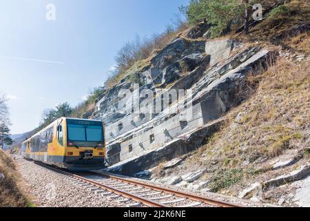 Spitz: Felsanker an der Felswand neben der Eisenbahnlinie, Felsformation Teufelsmauer, Zug der Wachaubahn von NÖVOG, Bahnlinie Donauuferbahn in Wachau, Stockfoto