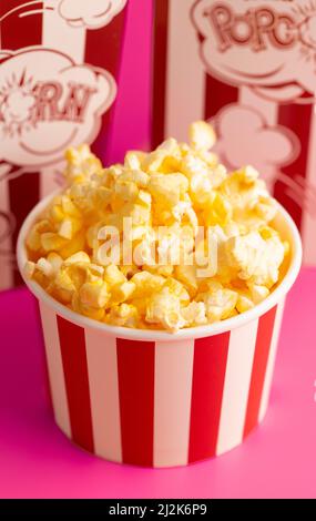 Rot-weiß gestreifter Popcorn-Eimer isoliert auf einem rosa Hintergrund Stockfoto