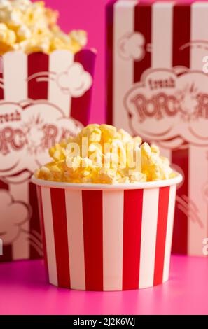 Rot-weiß gestreifter Popcorn-Eimer isoliert auf einem rosa Hintergrund Stockfoto