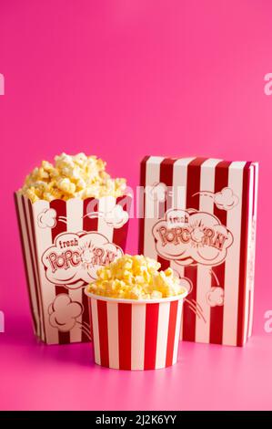 Rot-weiß gestreifter Popcorn-Eimer isoliert auf einem rosa Hintergrund Stockfoto
