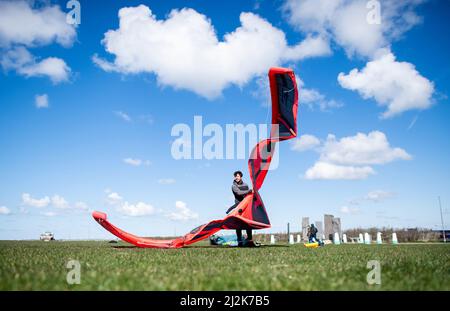 Norddeich, Deutschland. 02. April 2022. Jannis bereitet seinen Drachenfallschirm für das Kitesurfen an der Nordsee bei sonnigem Wetter vor. Am 04.04.2022 beginnen die Osterferien in Niedersachsen, Bremen und Schleswig-Holstein. Quelle: Hauke-Christian Dittrich/dpa/Alamy Live News Stockfoto