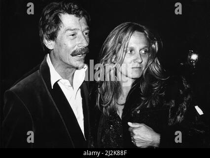 Der britische Schauspieler John Hurt kommt mit seiner Frau Donna in der Royal Albert Hall in London an, um das Musical "The Hunting of the Snark" zu besuchen, das auf Lewis Carrolls Gedicht basiert und vom Komponisten Mike Batt geschrieben wurde, wobei John Hurt die Narration zur Verfügung stellte. 1.. April 1987. Stockfoto