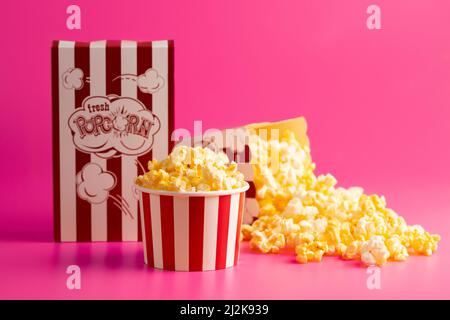 Rot-weiß gestreifter Popcorn-Eimer isoliert auf einem rosa Hintergrund Stockfoto