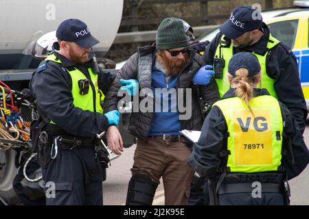 Grays, Thurrock, Großbritannien 2. April 2022 Stoppt einfach Öl Demonstranten blockieren Straßen am Thurrock Öldepot. Vier Demonstranten bestiegen einen Öltanker, der sich mit Schleusen auf dem Dach sicherte, während eine andere Gruppe eine Holzkonstruktion schuf, die einen Tunnel deckte, der unter der Straße ausgegraben wurde. Die vier Demonstranten wurden von den Rettungsdiensten mit einer Bahre entfernt und anschließend verhaftet. Kredit: Denise Laura Baker/Alamy Live Nachrichten Stockfoto