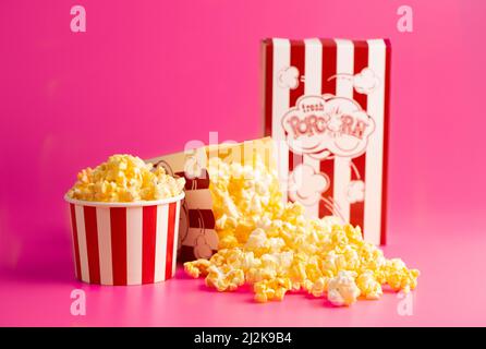 Rot-weiß gestreifter Popcorn-Eimer isoliert auf einem rosa Hintergrund Stockfoto