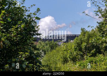 Retro-Dampfzug auf steingewölbtem Eisenbahnviadukt. Stockfoto