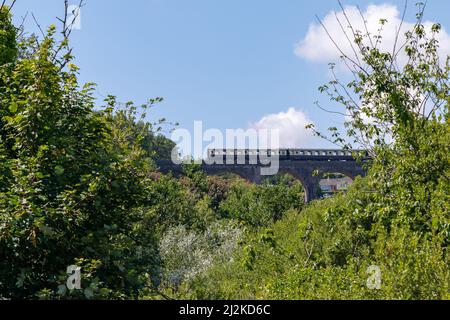 Retro-Dampfzug auf steingewölbtem Eisenbahnviadukt. Stockfoto