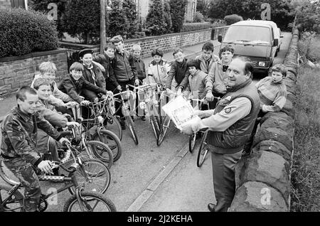 Eine Fahrradliste für den Radfahrer als Assistant District Commissioner (Scouts), Herr Jim Hunter (rechts), bereitet die Scouts des Distrikts Huddersfield South West auf ihre Reiterabzeichen vor. Rund 21 Jungen von Truppen durch den Südwesten waren im Scout-Hauptquartier von Crosland Moor, um ihr Abzeichen zu nehmen, das dazu gehört, ihre Fahrräder in einem verkehrsfähigen Zustand zu haben, zu wissen, wie man einen Reifenschaden flicken kann, Fragen zum Highway Code zu beantworten und eine kreisförmige Radroute zu absolvieren. 23.. Juni 1987. Stockfoto