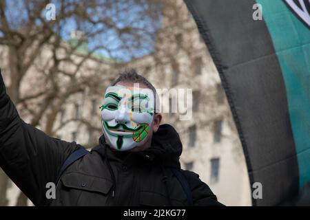 London, Großbritannien. 2. April 2022. Ein Mann mit einer Maske schwingt eine Flagge der hacktivistischen Gruppe Anonymous vor der Downing Street, wo sich Menschen versammelt haben, um gegen die steigenden Lebenshaltungskosten im Land zu protestieren. Quelle: Kiki Streitberger/Alamy Live News Stockfoto