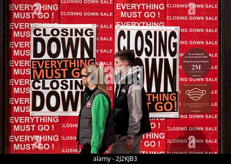 Pärchen, die an der 'Closing Down' vorbei gehen, alles muss gehen'-Schilder im Schaufenster eines Ladens auf der Princes Street, Edinburgh, Schottland, Großbritannien. Stockfoto