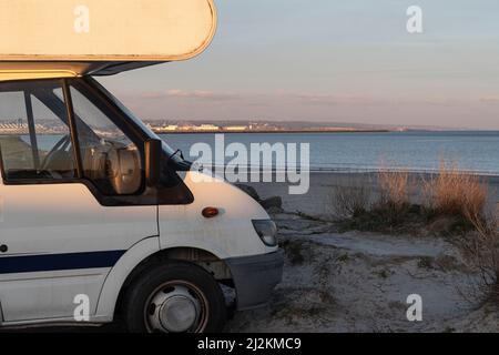 Ein Wohnmobil am Strand und am Meer geparkt, um die Nacht zu verbringen Stockfoto