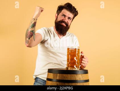 Glücklicher bärtiger Mann mit einem Becher Bier im Restaurant. Getränke, Alkohol und Freizeitkonzept. Oktoberfest. Stockfoto