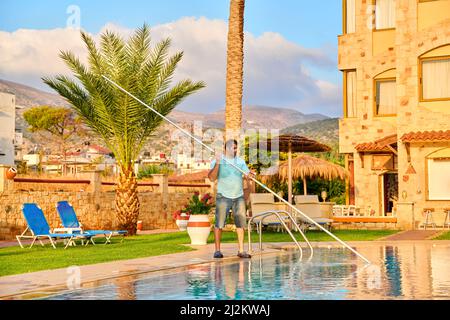 Mann, der den Außenpool putzt, schöne Aussicht auf die Natur im Hintergrund Stockfoto